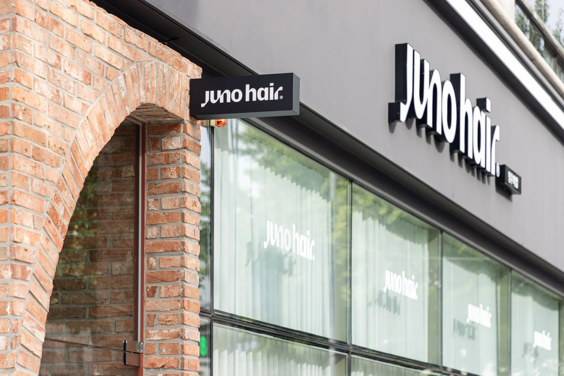 Brick arch entrance under the JUNO HAIR sign